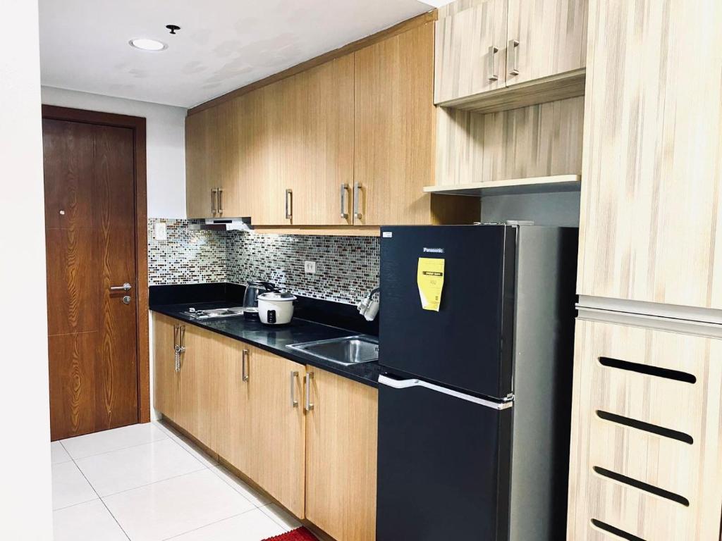 a kitchen with a black refrigerator and wooden cabinets at Sea Residences - Property Val Alano 0995-448-8872 in Manila