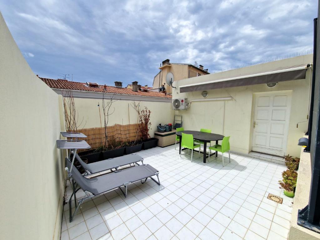 een patio met een tafel en stoelen op een huis bij Plein centre Appartement climatisé et spacieux avec grande terrasse sur le toit à Nice in Nice