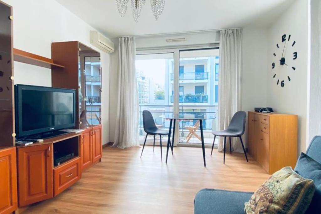 salon z telewizorem i stołem z krzesłami w obiekcie CityCosy ORANGERIE Strasbourg Appartement 2 pièces en face de parc de L'Orangerie avec un parking souterrain compris w Strasburgu