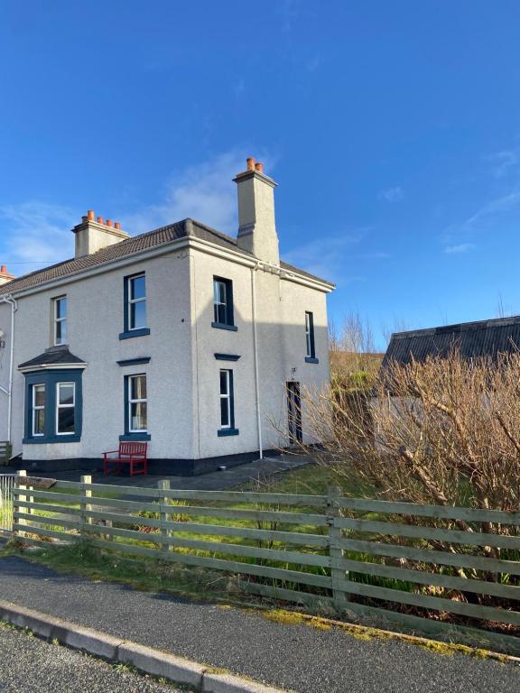 una casa blanca con una valla delante en Kilda House en Leverburgh