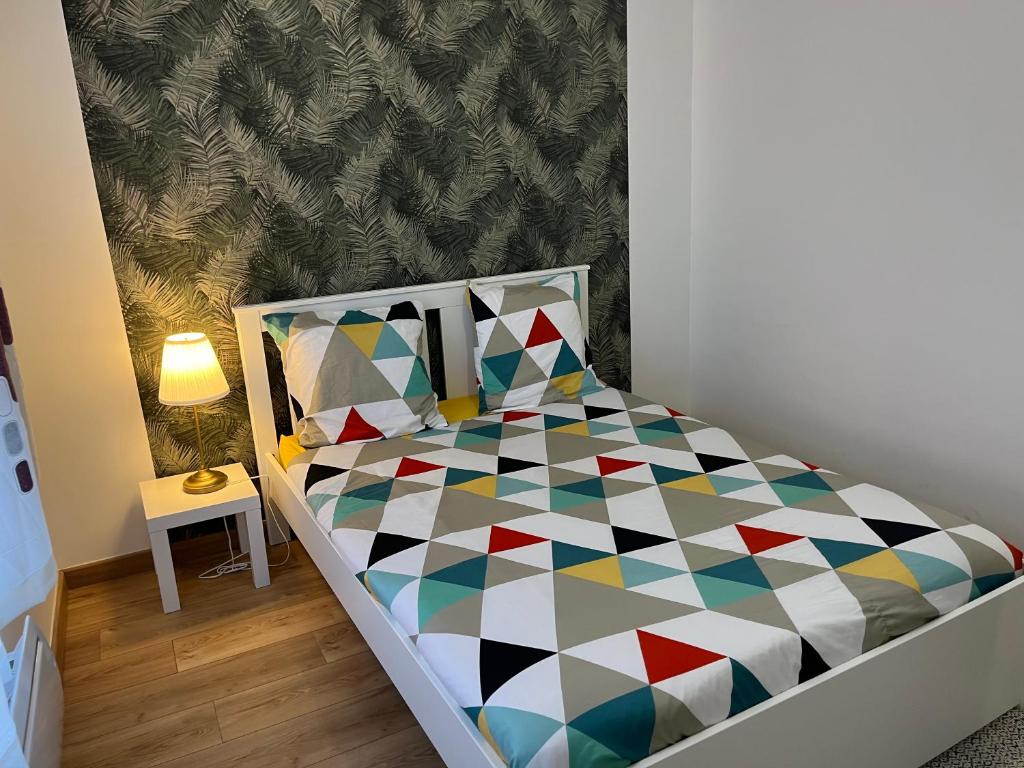 een kleine slaapkamer met een bed met een geometrisch patroon bij Magnifique appartement de 60m2 in Le Blanc-Mesnil