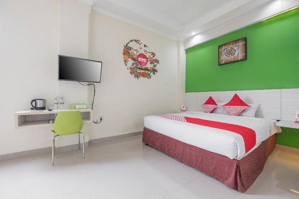 a bedroom with a bed with a green wall at Collection O 91714 Hotel Alden in Makassar