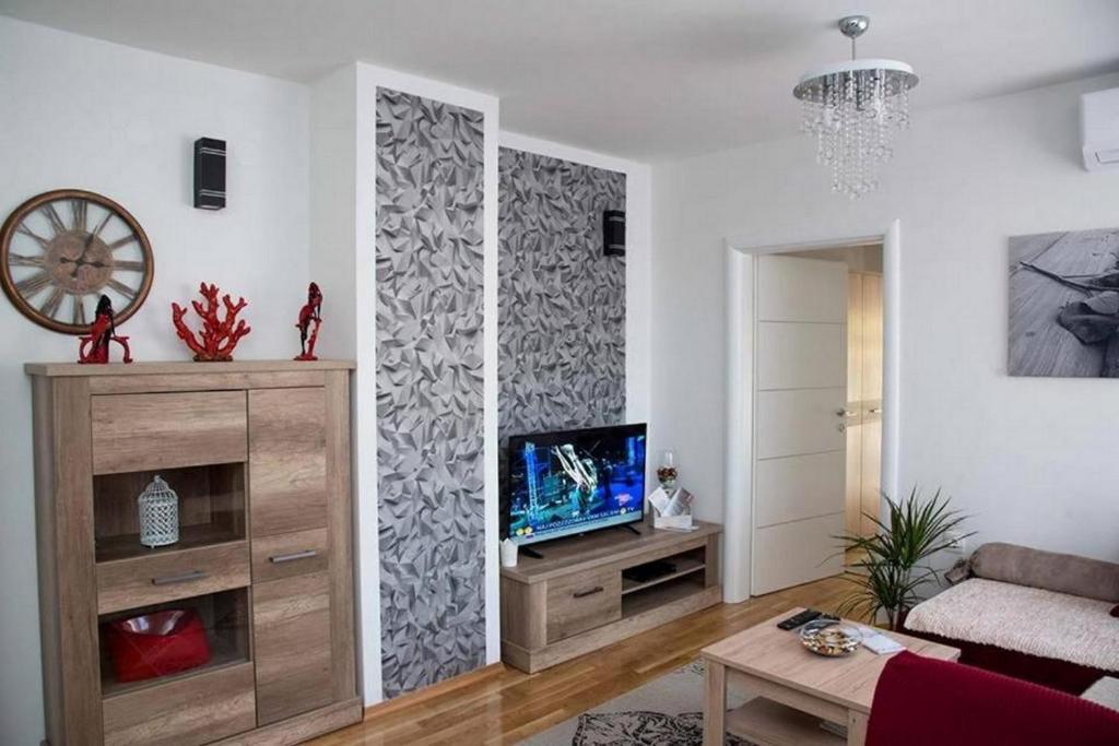 Apartments Oaza في داروفار: غرفة معيشة مع تلفزيون وجدار مع aarivascrift