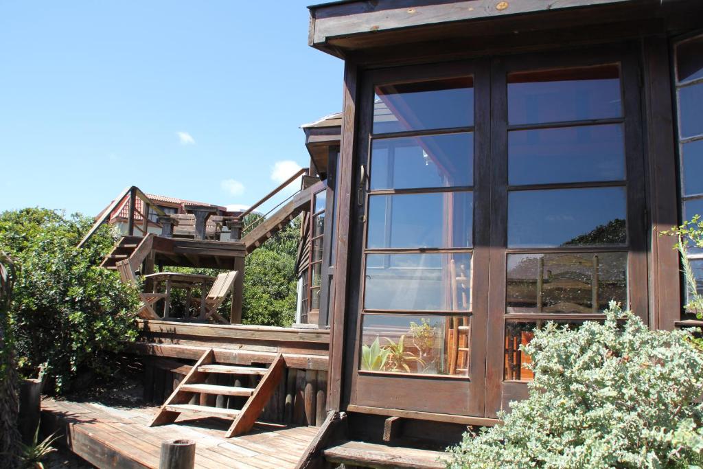 ein Haus mit einem großen Fenster und einer Holzterrasse in der Unterkunft Shack on Supers in Jeffreys Bay