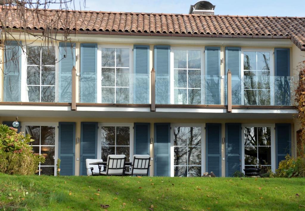 una casa con ventanas azules y sillas en el césped en Villa Rana en Lindau