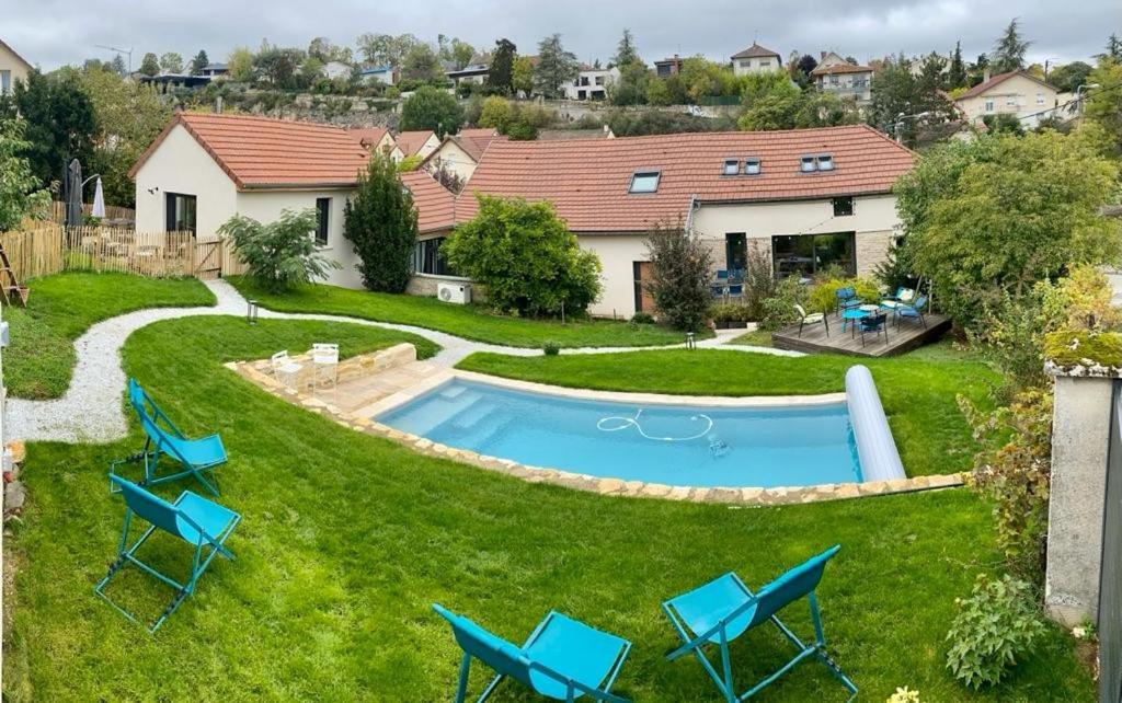 a backyard with a pool and chairs and a house at Proche centre ville, gîte 4 étoiles avec piscine in Dijon