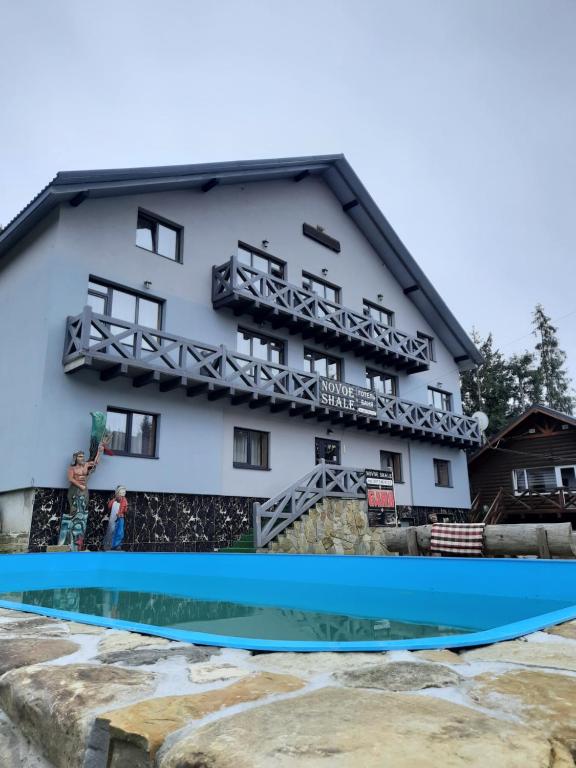 um edifício com uma piscina em frente em Hotel Novoe Shale em Yablunytsya