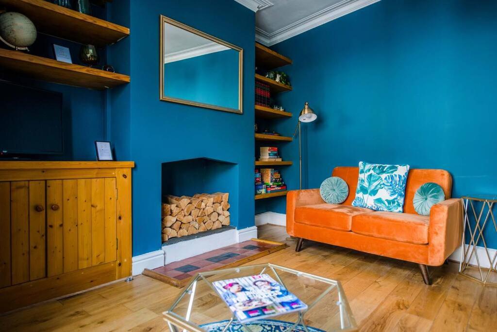 a living room with an orange couch and a blue wall at Gorgeous Victorian house sleeps 6 in Cardiff in Cardiff