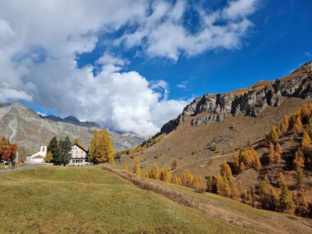 ein Haus auf einem Hügel mit Bergen im Hintergrund in der Unterkunft Hotel Sonne Fex Alpine Hideaway in Sils Maria