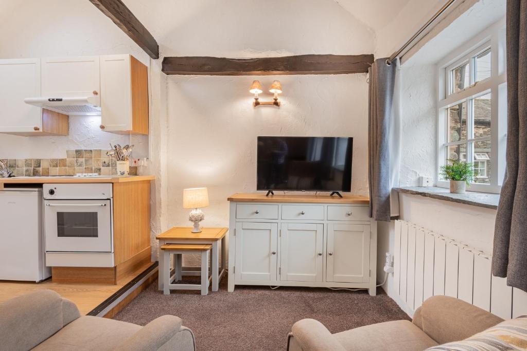 a living room with a tv and a kitchen at Cottage 6 Studio Mews in Keswick