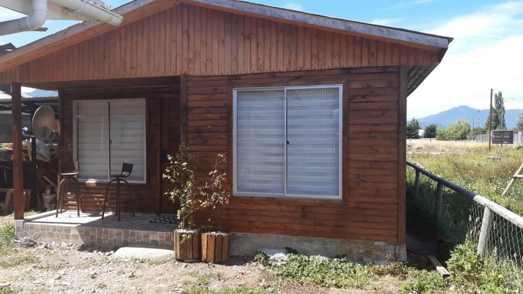 Cabaña pequeña con ventana y silla en Mi Cabaña, en Puerto Aysén