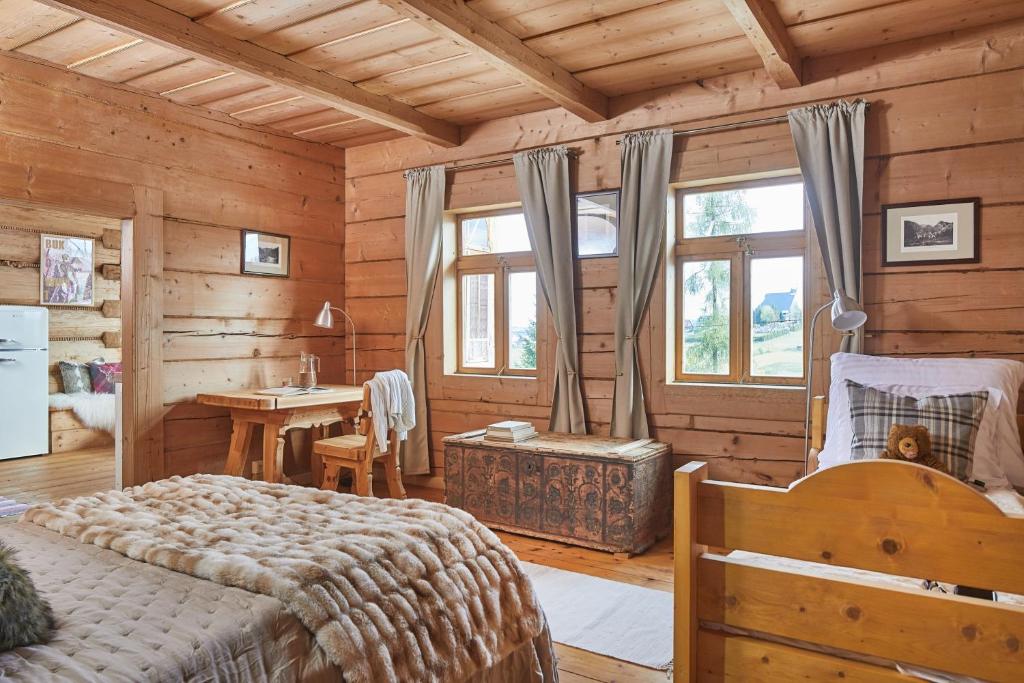 1 dormitorio en una cabaña de madera con cama y escritorio en Hruby Gazda - zabytkowa willa góralska na wyłączność en Bukowina Tatrzańska