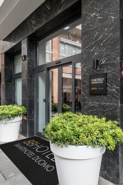 wejście do budynku z dwoma dużymi donicami roślin w obiekcie BB Hotels Smarthotel Duomo w Mediolanie