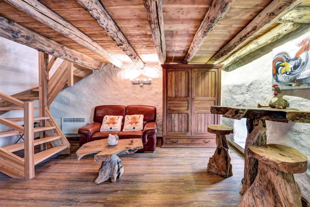 een woonkamer met een bank en houten plafonds bij LA FERME de BELLINE Chalets ou Gîtes & SPA in Briançon