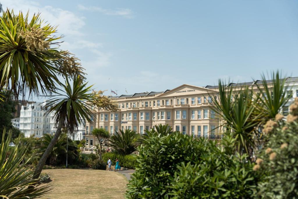ein großes Gebäude mit Palmen davor in der Unterkunft The Lansdowne, Eastbourne in Eastbourne