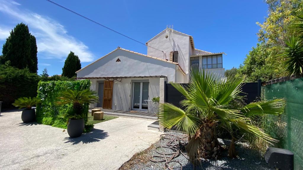 a white house with a fence and palm trees at Appartement verrière à deux pas des plages… in Hyères