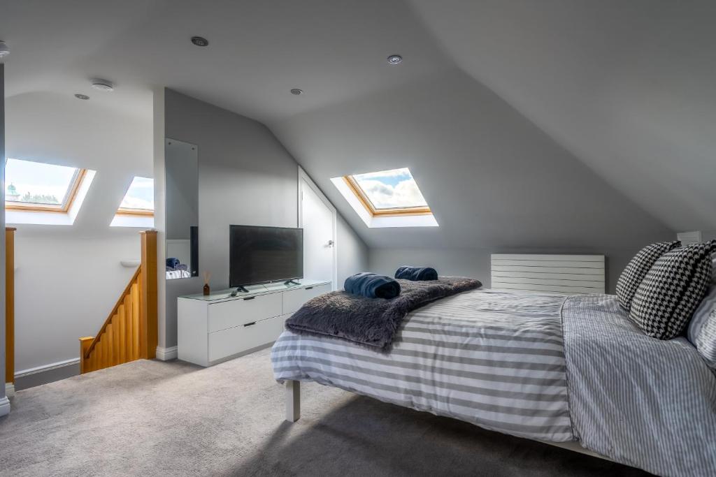 een slaapkamer met een bed, een tv en dakramen bij Craigey Beach Home in Edinburgh