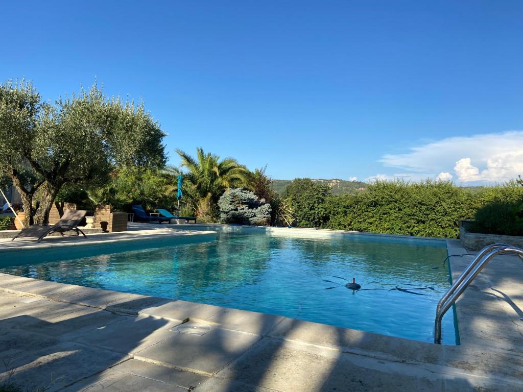 una gran piscina con agua azul y árboles en LE MAS D'ISACHRIS Le T2, en La Garde-Adhémar