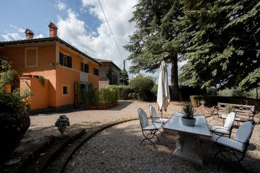 un patio con mesa y sillas y un edificio en White Elegant and Charming Country House near Rome, en Rocca di Papa