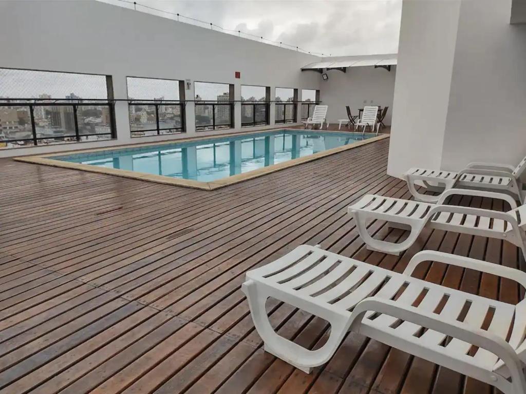 a deck with chairs and a pool on a building at Apto acolhedor, confortável e bem localizado in Campos dos Goytacazes