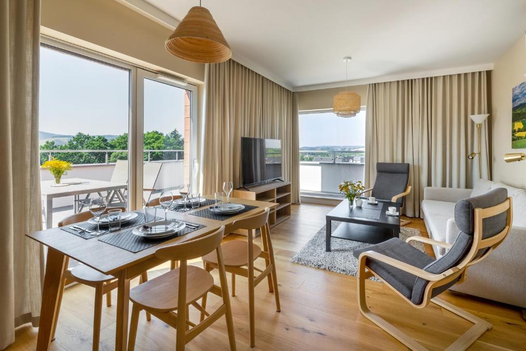 sala de estar con mesa, sillas y TV en Apartament Widokowy - Penthouse z tarasem en Kudowa-Zdrój