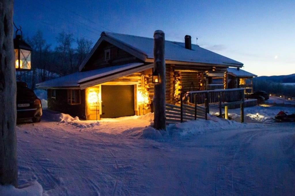 a log cabin in the snow at night at Kelo Aurora luxury cabin in Kilpisjärvi