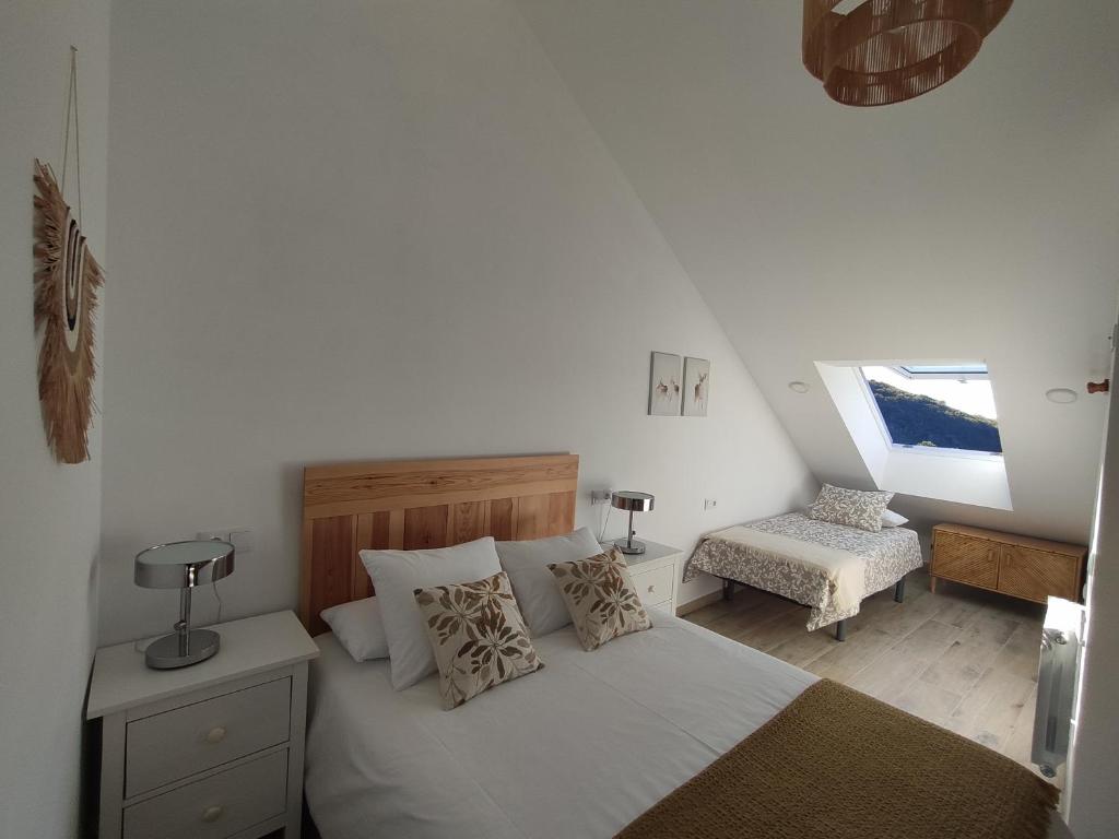 a bedroom with a white bed and a chair at CASA RURAL PAJARICA en Sanabria in San Ciprián