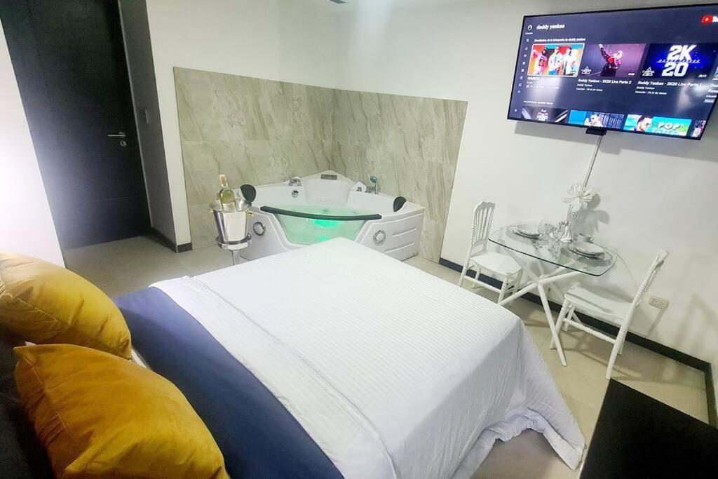 1 dormitorio con cama, bañera y TV en Ecusuites Jacuzzi Bellini Hidromasaje Privado, en Guayaquil