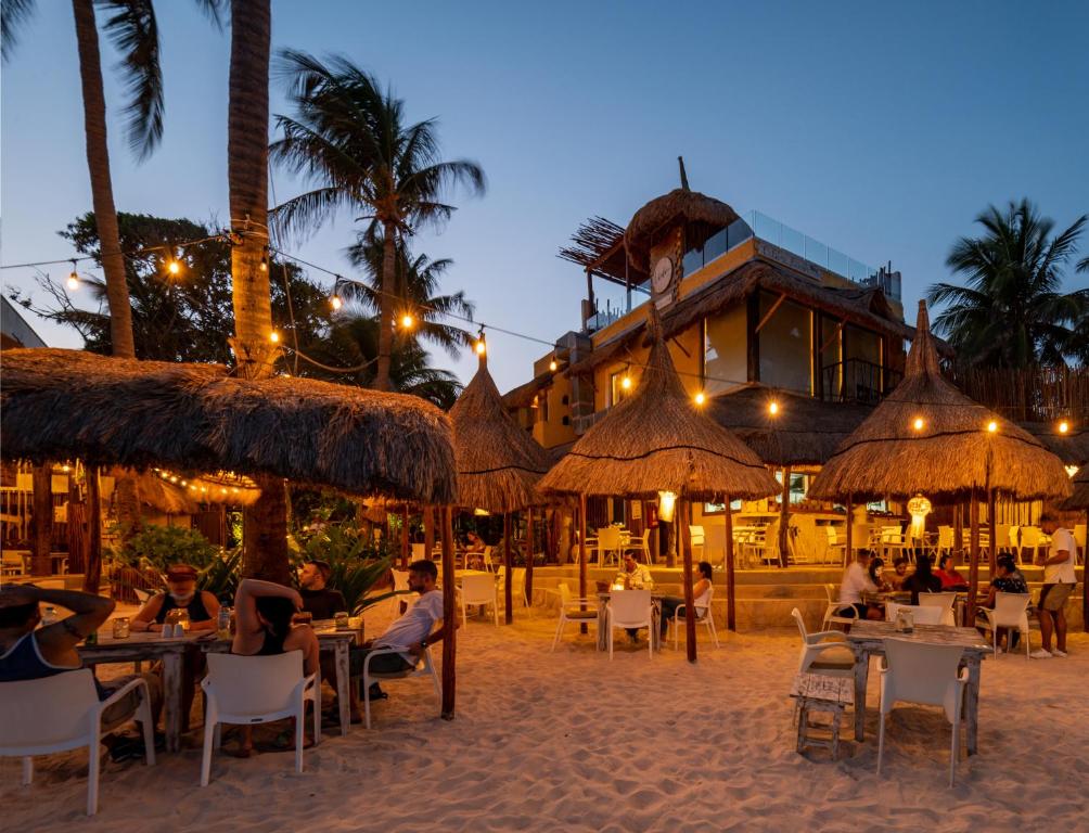 a group of people sitting at tables in front of a resort at Hotel Colibri Beach in Playa del Carmen