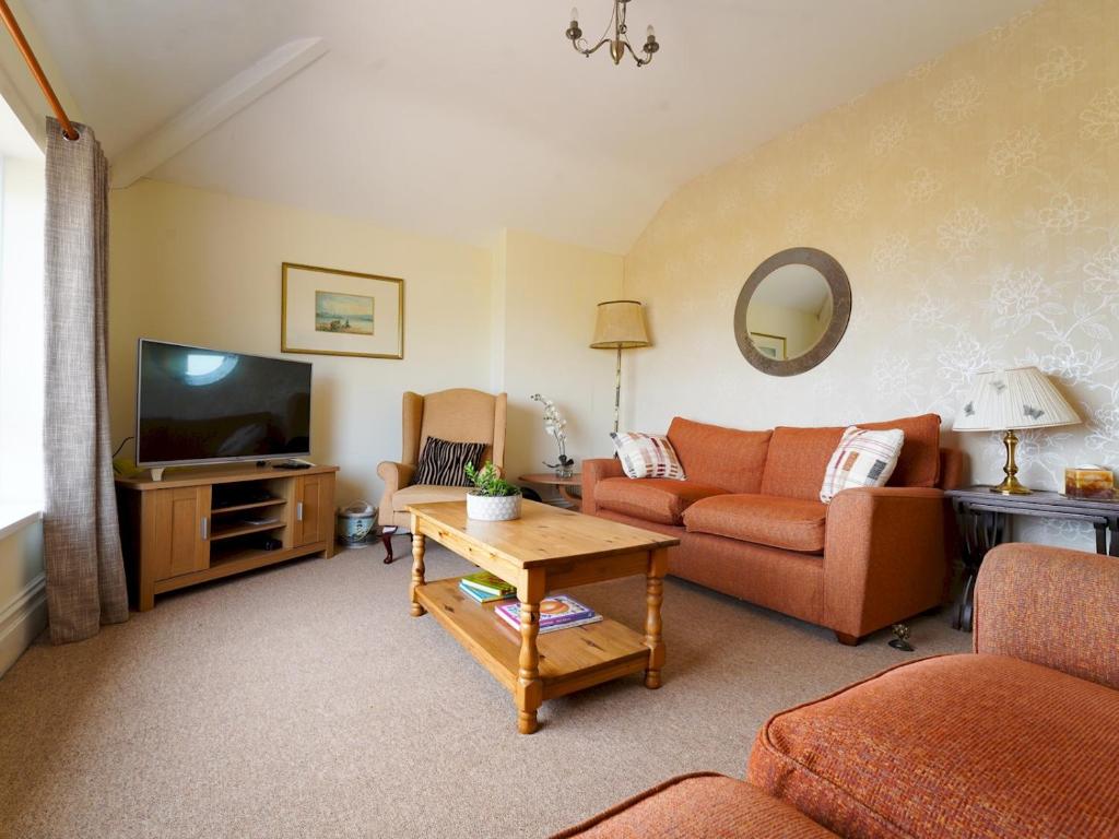 a living room with a couch and a tv at Pass the Keys Spacious 4 bed house overlooking Borth Beach in Borth