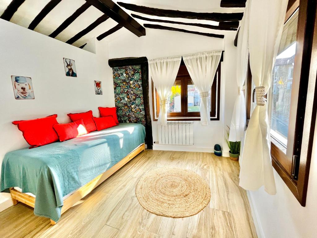 a bedroom with a blue bed with red pillows at La casita del rio in Soto en Cameros