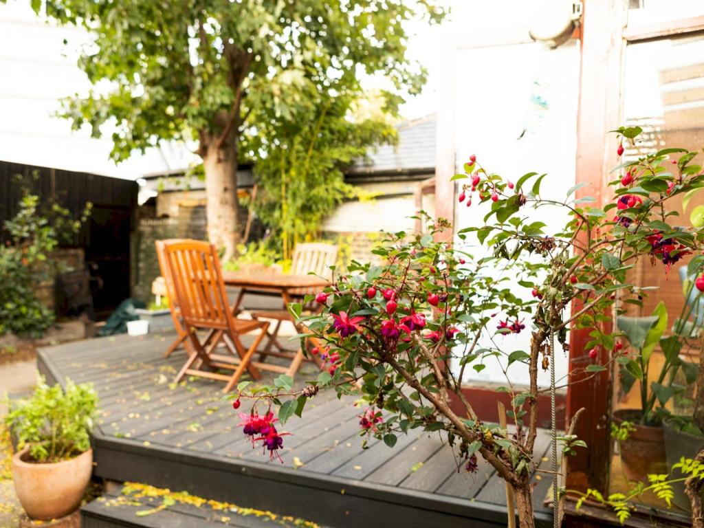un patio con mesa, sillas y flores en Pass the Keys Funky Garden House in Chiswick, en Londres