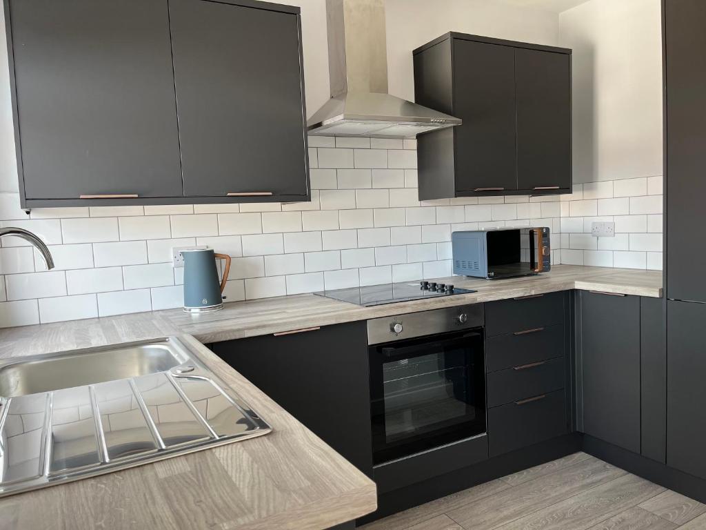 a kitchen with black cabinets and a sink at The Castlefield @ The Gathering - Sleeps Up To 5 in Sale