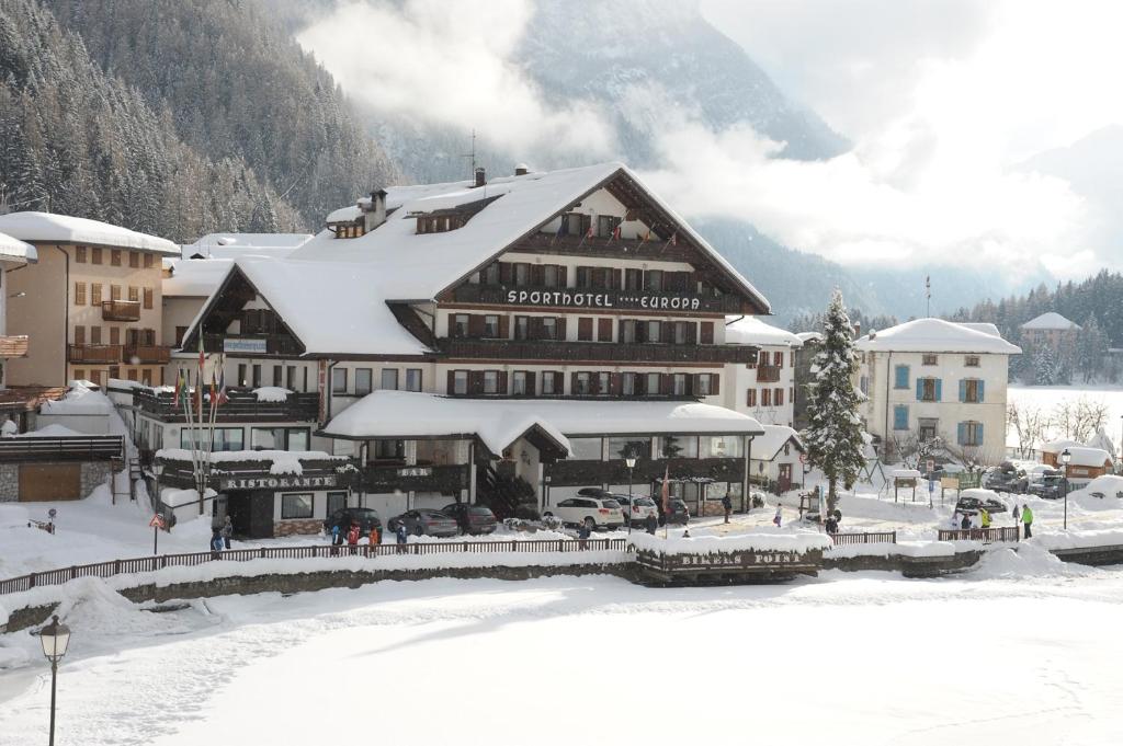 a large building with snow on top of it at Sporthotel Europa Sul Lago in Alleghe