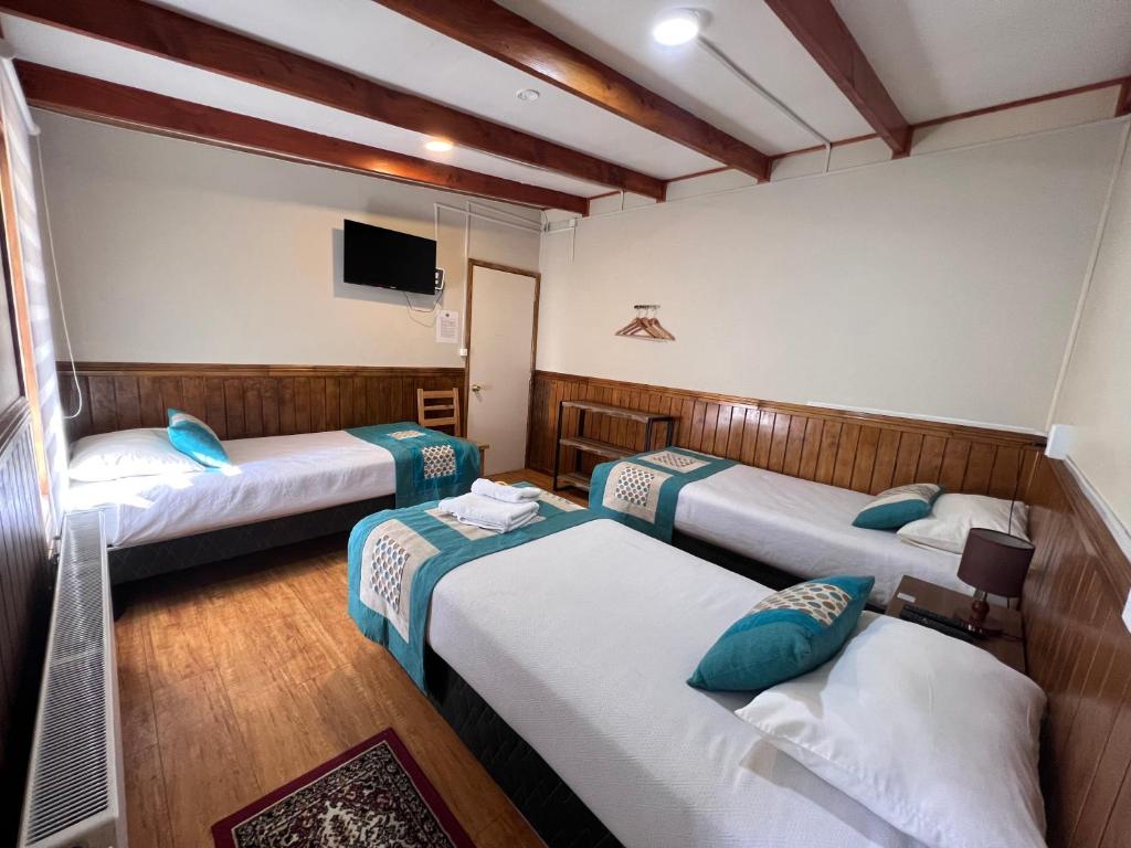 um quarto com três camas e uma televisão em Hostal Reymer Patagonia em Puerto Natales
