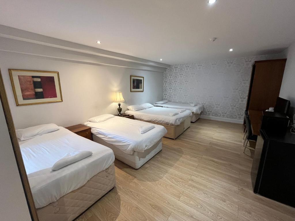 um quarto de hotel com três camas e uma televisão em Park View Rooms em Edimburgo