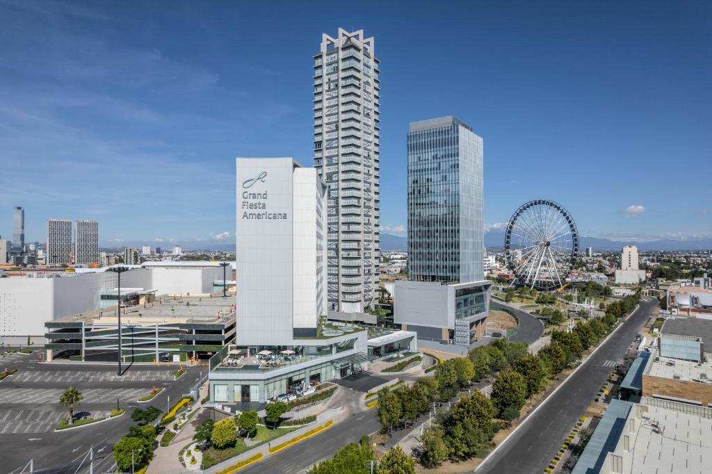 una ciudad con edificios altos y una noria en Grand Fiesta Americana Puebla Angelópolis, en Puebla