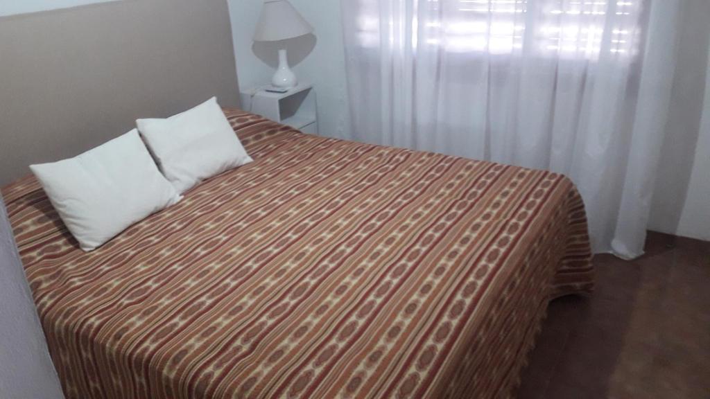 a bedroom with a bed with a striped comforter at Departamento Dorrego in Trenque Lauquen