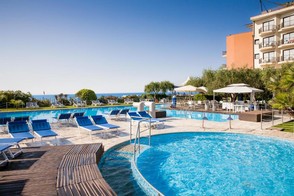a swimming pool with chairs and a hotel at Grand Hotel Diana Majestic in Diano Marina