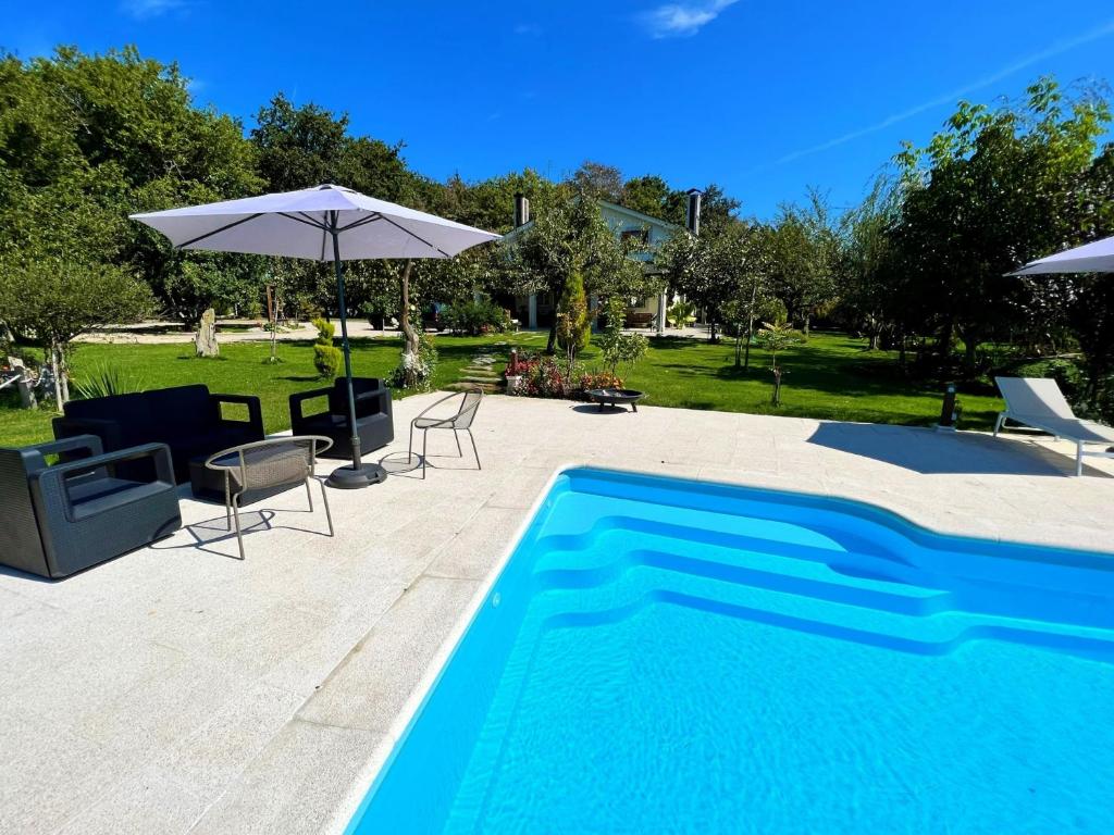 a swimming pool with chairs and an umbrella at Villa Albaredo in Villameá