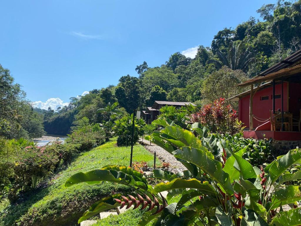 a garden in front of a red building with trees at Playa Selva Lodge in Archidona