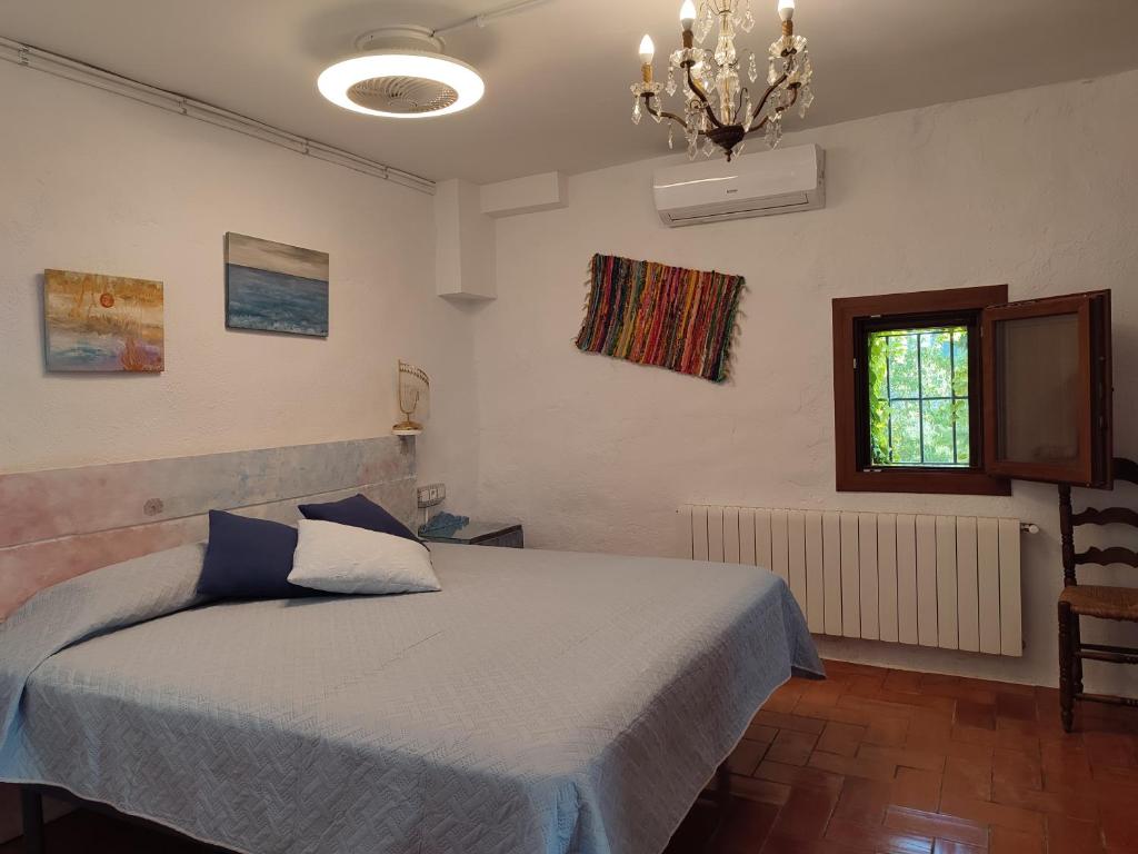 1 dormitorio con cama, ventana y lámpara de araña en Romegosa Benestar, en Sant Marçal
