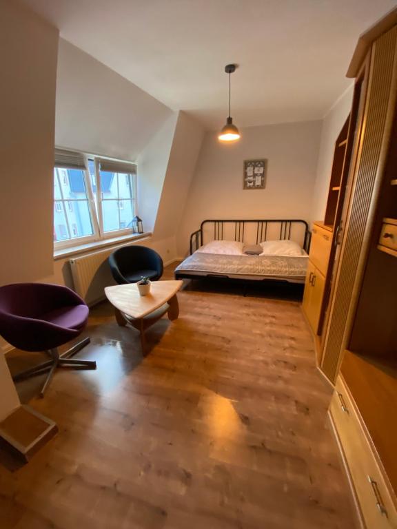 een slaapkamer met een bed en 2 stoelen en een tafel bij Bezauberndes Stadtidyll in Lichtenstein