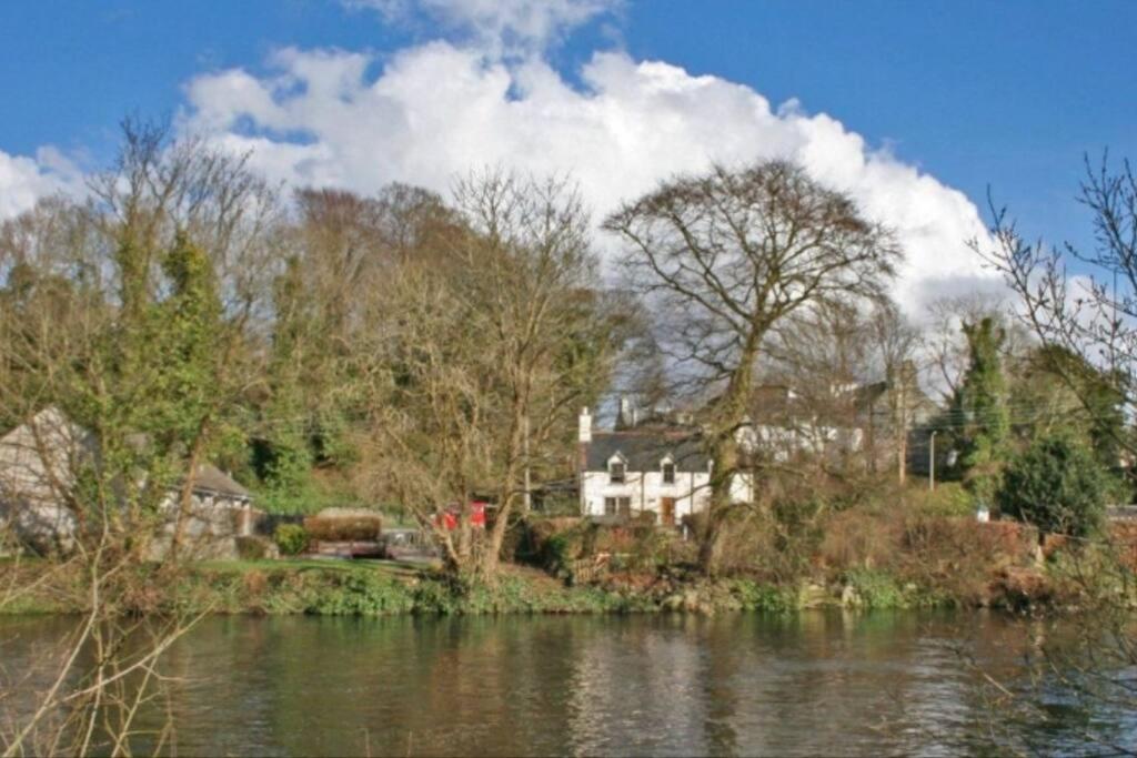 a house sitting on the side of a river at Woodbank Cottage Newton Stewart in Newton Stewart