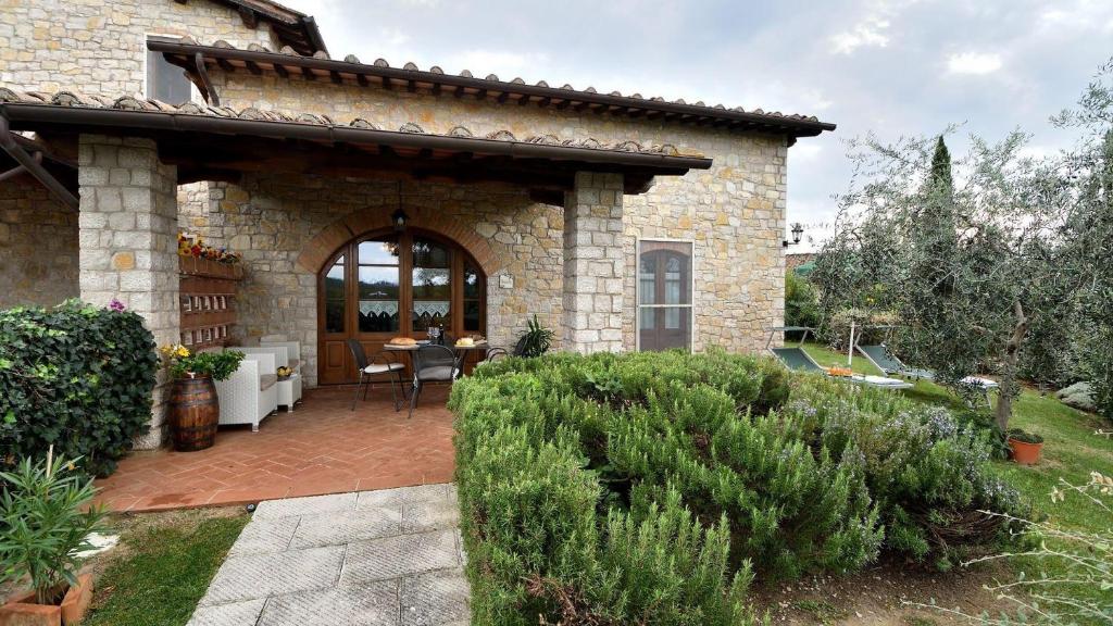 een stenen huis met een patio met een tafel bij Villa Violetto in Gaiole in Chianti