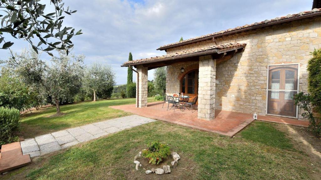 a stone house with a patio in a yard at Villa Fiorella in Gaiole in Chianti