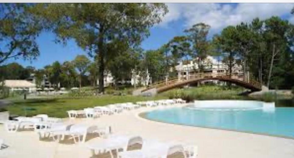 a swimming pool with white chairs and a bridge at Green Park in Punta del Este