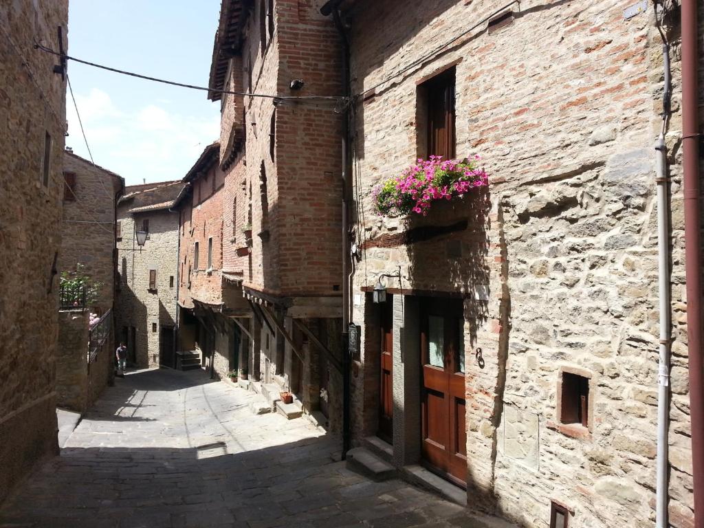 an alley in an old building with flowers in a window at Casina Iannelli in Cortona