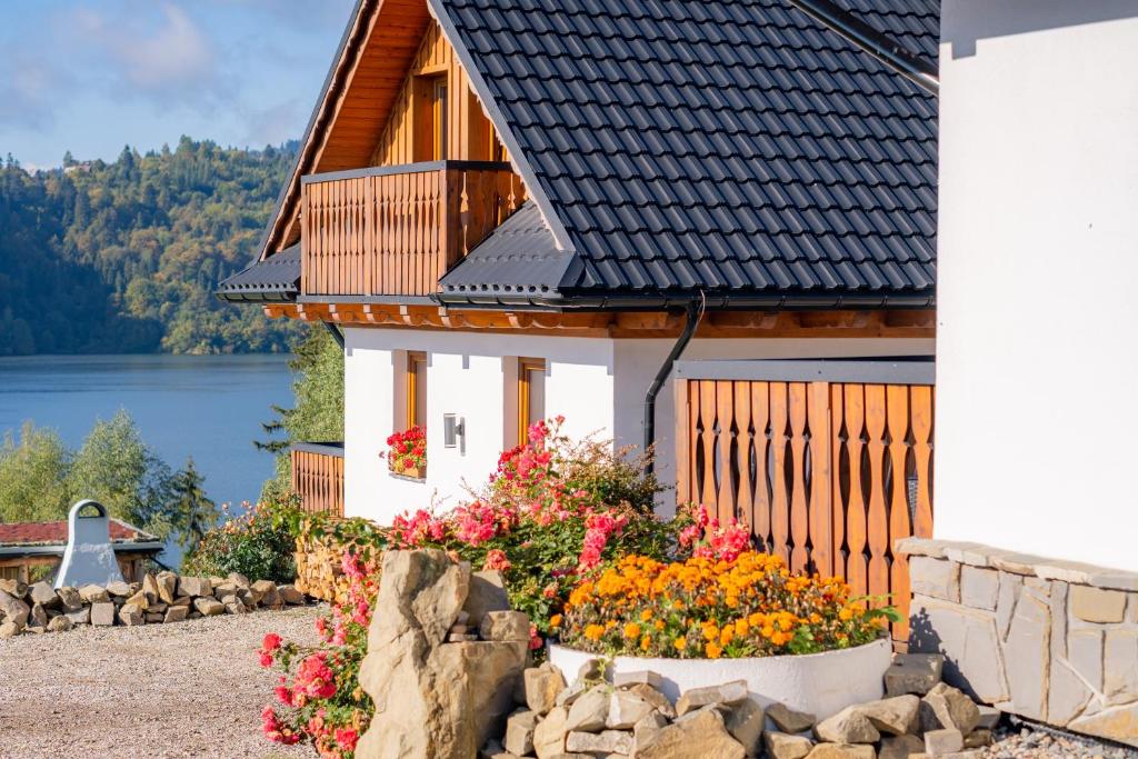 una casa con flores frente a un lago en Osada Brzezia, en Kluszkowce