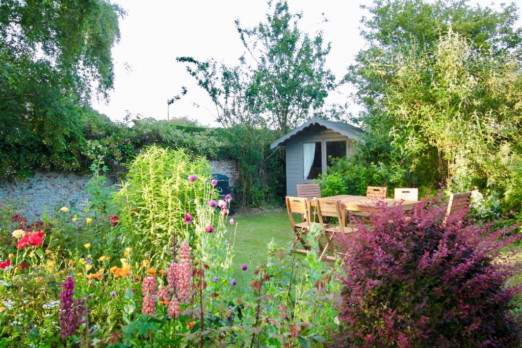 a garden with a table and chairs and flowers at Duck Cottage - Grade II Listed cottage, village location, nr Holt in Letheringsett